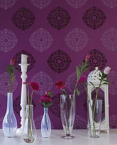 five vases with flowers in them are lined up against a wallpapered background