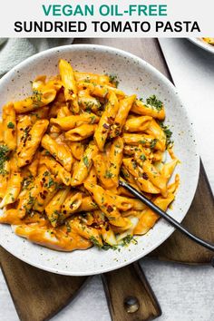 a bowl filled with pasta and sauce on top of a wooden cutting board next to two bowls