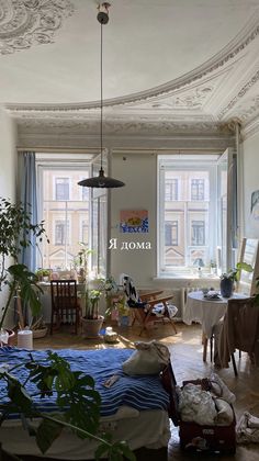 a living room filled with furniture and lots of windows next to a bed covered in blankets