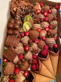 a box filled with lots of different types of chocolates and strawberries on top of ice cream cones