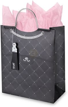 a black shopping bag with pink tissue paper on it and a chain around the handle