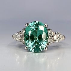 🐕 Big deals! Oval cut teal green tourmaline ring 14K solid gold paraiba tourmaline engagement ring Unique vintage moissanite wedding ring for women #7326 only at $828.00 Hurry. #CustomRing #ParaibaTourmaline #ModernRing #WeddingRing #HandmadeJewelry #ClusterRing #MoissaniteDiamond #AlternativeRing #OvalCutShaped #EngagementRing Elegant Green Oval Topaz Ring, Elegant Green Aquamarine Rings, Oval Moissanite Emerald Green Ring, Oval Green Moissanite Emerald Ring, Oval Emerald Moissanite Ring, Green Aquamarine Ring With Center Stone, Green Oval Topaz Ring For Wedding, Oval Emerald Ring With Moissanite And Accent Stones, Paraiba Tourmaline Engagement Ring