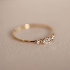 a gold ring with two pear shaped diamonds on the side, sitting on a white surface