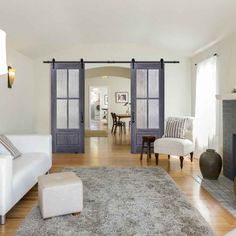 a living room with white furniture and blue doors