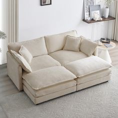 a living room with a large sectional couch and white rugs on top of the floor