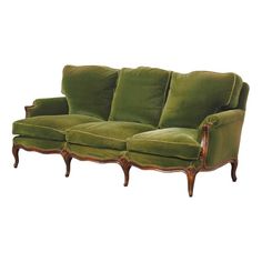 a green velvet couch with wooden legs and arm rests against a white wall, in the style of louis ii