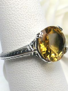 Natural Yellow Citrine Art Deco RingButton Design#D12 Introducing a radiant symbol of warmth and vitality – our Natural Yellow Citrine Art Deco Ring. This exquisite piece of jewelry is a stunning blend of vintage charm and contemporary elegance, meticulously crafted to captivate hearts and turn heads. Crafted in sterling silver, this Art Deco reproduction ring is a true testament to timeless beauty and exceptional craftsmanship. Set with a mesmerizing 3-carat natural yellow citrine gemstone, thi Classic Orange Topaz Round Ring, Yellow Topaz Round Ring, Oval Citrine Ring With Spiritual Style, Yellow Citrine Round Cut Rings, Classic Yellow Topaz Ring With Center Stone, Yellow Topaz Ring With Center Stone, Spiritual Oval Citrine Ring, Yellow Spiritual Round Jewelry, Art Deco Citrine Rings In Yellow