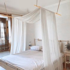 a bed with white drapes hanging from it's sides