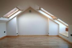 an empty room with wooden floors and skylights