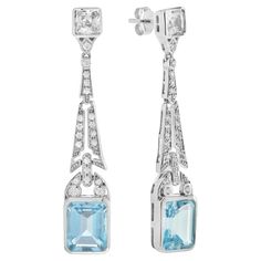 Top off your look with this spectacular pair of earrings. Coordinate them with your favorite outfit for a brilliant and lively appearance. The top of the solitaire drop earrings shows a beautiful cluster of round diamonds, in which the stunning spray design gently dangles below with the emerald cut blue topaz. Information Metal: 14K White Gold Width: 9 mm. Length: 50 mm. Weight: 9.18 g. (approx. in total) Backing: Push Back Center Gemstones Type: Blue Topaz Shape: Emerald Size: 10x8 mm. Number: Formal Blue Topaz Diamond Earrings Fine Jewelry, Formal Blue Topaz Diamond Earrings, Dazzling Diamond Gemstone Earrings For Formal Occasions, Dazzling Diamond Gemstone Earrings For Formal Events, Elegant Blue Diamond Cut Earrings, Formal White Gold Earrings With Blue Topaz, Elegant Blue Diamond Dangle Earrings, Luxury Blue Topaz Drop Earrings, Formal Platinum Earrings With Gemstone