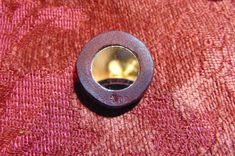 a small round object sitting on top of a red cloth covered tablecloth with a metal ring in it's center