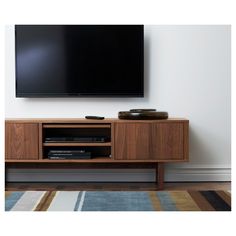 a flat screen tv sitting on top of a wooden entertainment center next to a rug