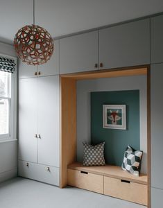 a room with white and blue walls, cabinets and a window in the corner that has a light fixture hanging above it