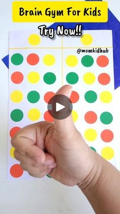 a hand is pointing at a colorful dot pattern on a sheet of paper that says brain gym for kids try now