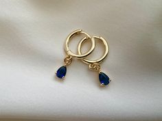 Sapphire blue gold plated hoop earrings with beautiful dangly blue cubic zirconia charm Gold plated brass hoops Hoop size approximately 14mm Charm size approximately 5mm Every order comes in our luxury matt frosted recyclable logo pouch, which are also available to purchase separately for any extra pieces you may want to store with style. Gift wrap sets (box & faux leather pouch)  are available at checkout and available to buy separately. Blue Cubic Zirconia Hoop Earrings As Gift, Blue Cubic Zirconia Hoop Earrings For Gift, Blue Gold-plated Hoop Earrings For Pierced Ears, Gift Sapphire Hoop Earrings, Sapphire Hoop Earrings As Gift, Blue Tarnish Resistant Huggie Jewelry, Blue Tarnish-resistant Huggie Jewelry, Blue Hoop Earrings Gold Plated, Blue Dangle Huggie Earrings As Gift