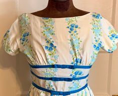 "This is a very pretty vintage dress from the late 1950's or very early 1960's. It is a petite size, and is a 22 inch waist. It is a very nice cotton fabric (almost a cotton sateen) with alternating stripes of pain cream and white with blue flowers and green leaves.  The waist has 3 bands of dark blue finished with bows. The waist is gathered in pleats. It has a metal and cloth zipper. The dress has a Jonathan Logan Label.  Condition is good- with only a tiny pen mark on the skirt, not really no Vintage Cotton Dress For Garden Party, Fitted Cotton Vintage Dress For Garden Party, Cotton Vintage Dress For Garden Party, Retro Cotton Vintage Dress With Vintage Pattern, 1950s Style Lined Cotton Vintage Dress, 1950s Cotton Vintage Dress, 1950s Cotton Vintage Dress For Vintage Fashion Events, 1950s Cotton Vintage Dress For Spring, 1950s Style Cotton Vintage Dress