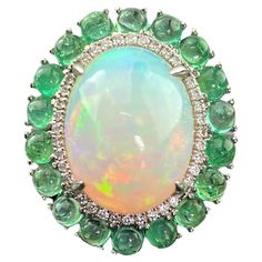 A statement Opal and Colombian Emerald cabochon cocktail ring, with White Diamonds. This enchanting ring combines the lush green of emerald with the captivating beauty of an oval-shaped opal at its heart. Details: 18K Gold - 8.13 Grams Diamond Round - 0.23 carat Emerald - 2.59 Carat Opal -5.64 Cts Elegant Cabochon Emerald Ring, Elegant Emerald Ring With Cabochon Cut, Elegant Emerald Cabochon Ring, Green Gemstone Cabochons For Formal Use, Luxury Green Cabochons, Fine Jewelry Green Cabochons For Formal Occasions, Elegant Green Cabochon Emerald Ring, Elegant Green Emerald Cabochon Ring, Green Cabochons For Formal Fine Jewelry