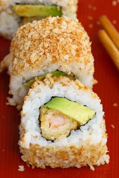 two pieces of sushi on a red plate with chopsticks next to it