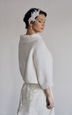 a woman wearing a white sweater and skirt with flowers in her hair is looking off to the side