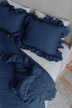 an unmade bed with blue sheets and pillows