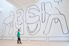 a man standing in front of a large wall with graffiti on it's side