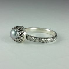 a white gold ring with a pearl in the center and filigrees around it