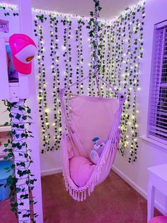 a pink hammock hanging from the ceiling in a room decorated with vines and lights