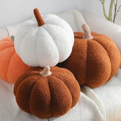 three orange and white pumpkins sitting on top of a bed next to each other