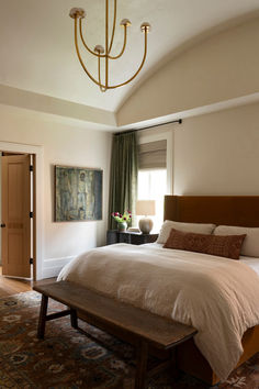 a bedroom with a large bed and a wooden bench in front of the window,