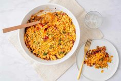 a white bowl filled with food next to two plates