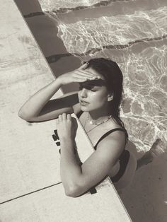 a woman sitting on the edge of a swimming pool with her hands to her face