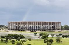 a rainbow shines in the sky over a large building that has a circular roof