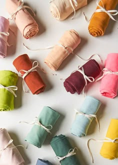 several rolls of colored paper tied together with twine on white table top, next to each other