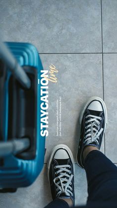 a person standing next to a blue piece of luggage on top of a tile floor