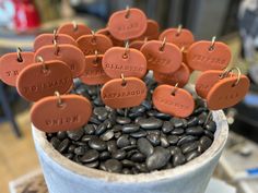 a pot filled with lots of brown tags on top of black rocks and coffee beans