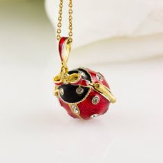 "Bright and festive ladybug locket with heart surprise inside, enameled and 24 K gold plated over solid sterling silver, designed and made in our NJ shop in the tradition of Faberge jewelry. The egg shaped locket ladybug with bright red wings and a black head, will open to show the heart inside the locket, steadily fixed in its place. Clear Swarovski crystals are set in the center of the heart, as well as in the dots of the bug and its eyes. The locket is almost 1\"(25 mm) long. You will receive Luxury Red Necklace For Gift, Red Round Jewelry With Black Enamel, Luxury Red Jewelry For Gift, Enamel Locket Jewelry For Gifts, Red Jewelry For Valentine's Day Keepsake, Black Enamel Oval Necklace For Gift, Black Enamel Oval Necklace As Gift, Oval Black Enamel Jewelry Gift, Yellow Gold Enamel Necklace For Gift