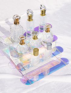 an assortment of perfume bottles sitting on top of a glass tray in front of a white background