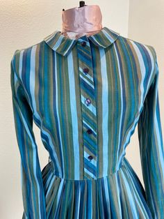 "1960's Blue And Green Stripe Shirt Dress This is such a great shirt dress. The stripes and the careful placement of them make this shirt dress next level attractive. Just check out the pictures and see how the stripes were perfectly utilized to make a regular cut shirt dress into something special. This dress is a button front closure, has her makers tag, which is frayed. Maker is Carol Rodgers Juniors Measurements provided are flat and have been doubled. Bust 34\" Waist 25\" Hips free\" Length Fitted Striped Long Sleeve Shirt Dress, Striped Fitted Cotton Shirt Dress, Fitted Striped Cotton Shirt Dress, Striped Cotton Shirt Dress With Buttons, Fitted Striped Shirt Dress With Buttons, Retro Blue Button-up Dress, Fitted Striped Shirt Dress For Daywear, Vintage Long Sleeve Striped Dresses, Vintage Striped Workwear Dresses