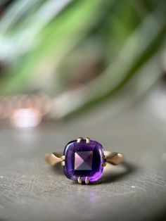 "This antique amethyst ring is utterly divine, with a rich solid 18ct gold band that really ignites that lavender-hued gemstone.  The amethyst is an unusual 'buff-top' cut, with a faceted bottom and smooth cabochon top, in the shape of a classic cushion cut. It is held securely in place by 4 double prongs on an 18ct gold setting.  The band is simple at the back, with just a touch of detail near the shoulders which taper to a point leading to that gorgeous stone. If you are intrigued by the world of spiritual healing, amethyst is thought to help ease sadness and alleviate stress. Sounds good to me!  Hallmarks: \"18CT\" tested as 18ct gold.  Condition: Very good condition. This ring still looks fab for an antique piece, the gold has turned buttery soft and still lovely and bright. There is a Timeless Purple Rings For Gifts, Timeless Purple Rings As Gifts, Timeless Purple Rings Perfect For Gifts, Timeless Purple 14k Gold Rings, Heirloom 14k Gold Solitaire Amethyst Ring, Heirloom Solitaire Purple Amethyst Ring, Purple Amethyst Ring In 14k Gold, Heirloom Yellow Gold Amethyst Solitaire Ring, Timeless Amethyst Promise Ring