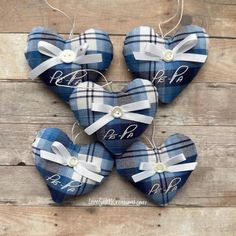 three blue plaid heart ornaments with white ribbon and monogrammed names hanging on wood planks