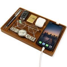 an iphone, watch, and other items are arranged on a wooden tray