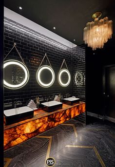 a bathroom with three sinks and two mirrors on the wall next to each other in front of a black brick wall