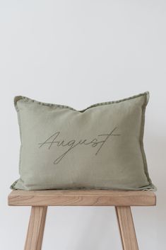 an embroidered pillow with the word august on it