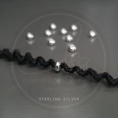 several silver balls are placed in the middle of a black string on a gray surface