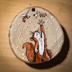 a hand painted wooden ornament with a cat on it's back holding berries