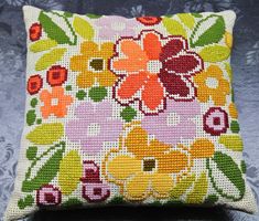 a cross stitch pillow with flowers on it