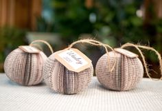 three balls of yarn with tags on them sitting on a white tablecloth covered table