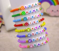 a stack of bracelets sitting on top of a white table next to a rainbow wall