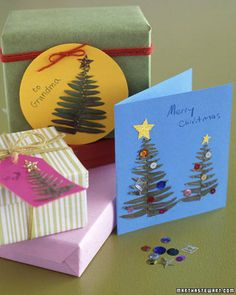 three christmas cards are sitting on a table next to a box with a card in the shape of a christmas tree