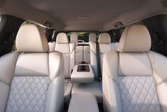 the interior of a car with all white leather seats and center console, facing forward